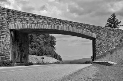 Road by bridge against sky