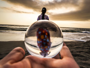 Lensball on human hand with beautiful object and sunset panorama