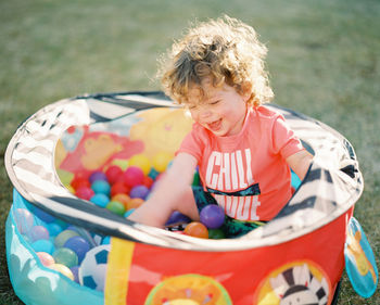 High angle view of cute boy sitting in ball pool