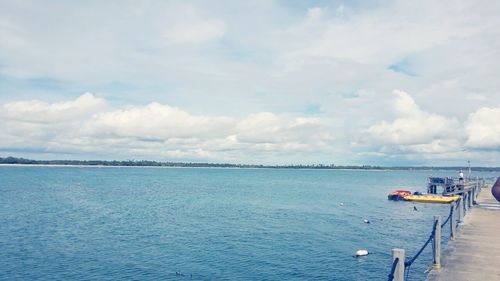 Boats in sea against cloudy sky