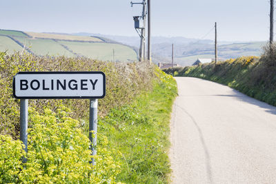 Road sign by trees against sky