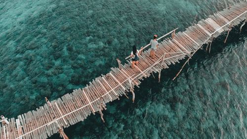 High angle view of people standing on bridge over sea