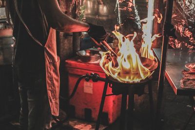 Midsection of man preparing food at market stall during night