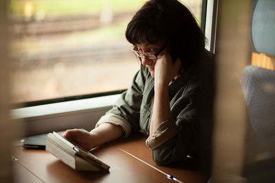 Mature woman using digital tablet in train