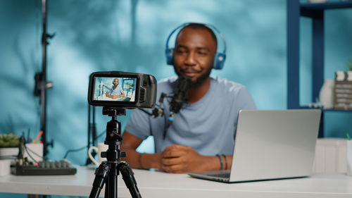 Smiling young man filming through camera