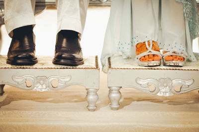 Low section of bride and bridegroom on footstool