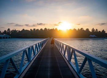 Pier over sea against sky during sunset