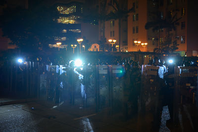 People on illuminated street amidst buildings in city at night