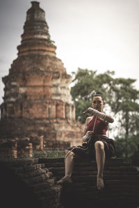 Woman sitting on temple against sky