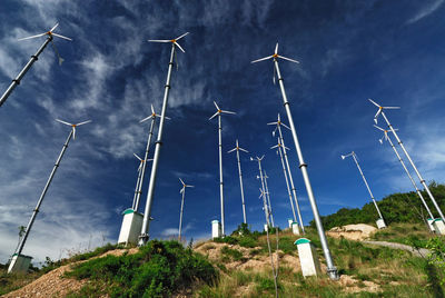 Low angle view of wind turbines against blue sky