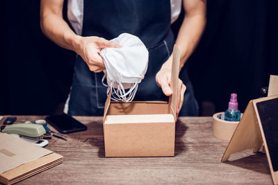 Midsection of woman packing masks in box on table