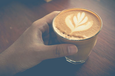 Cropped image of hand holding coffee cup on table