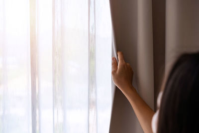 Rear view of woman touching window