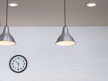 Low angle view of illuminated pendant lights hanging on wall