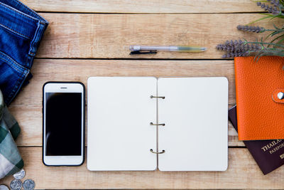 Directly above shot of open book and mobile phone on table