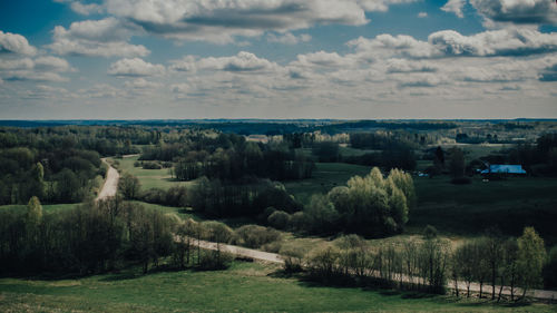 Scenic view of landscape by woods and fields against sky