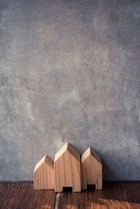 Close-up of model home on wooden table by wall