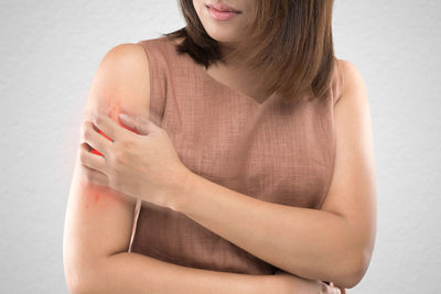 Midsection of mid adult woman with wounded hand while standing against wall