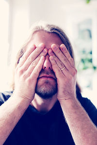 Portrait of man covering face with hand