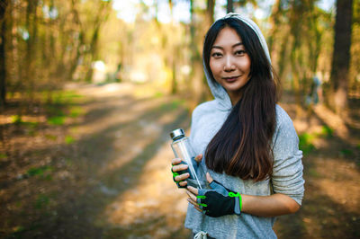 Sport woman holding bottle of water looking at camera outdoors.