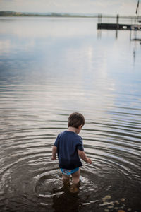 Rear view of boy standing in lake