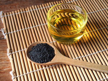 Black sesame seeds in wooden spoon and a glass of oil.