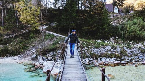 Rear view of man on footbridge over river