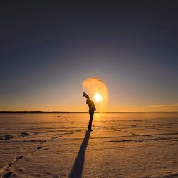 Silhouette man standing on beach against sky during sunset