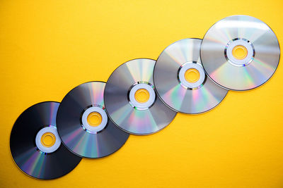 Close-up of compact discs over yellow background