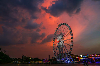 Low angle view of illuminated ferris wheel against sky at sunset