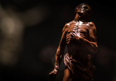 Midsection of shirtless man standing against black background