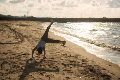 Asian athlete woman in running outfit suit somersault on rayong beach at sunrise