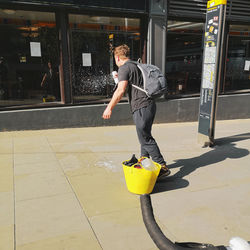 Full length of man holding umbrella in city