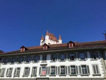 Low angle view of building and thun castle against clear blue sky