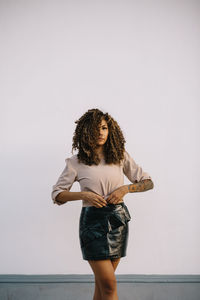 Portrait of young woman standing against wall