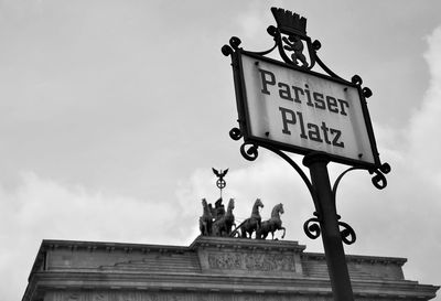 Low angle view of sign board against cloudy sky