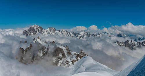 Panoramic view of snowcapped mountains against blue sky