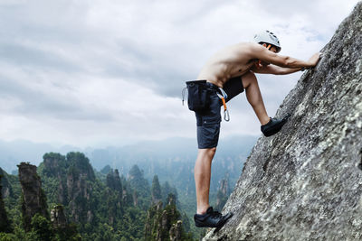 Full length of man standing on rock against sky