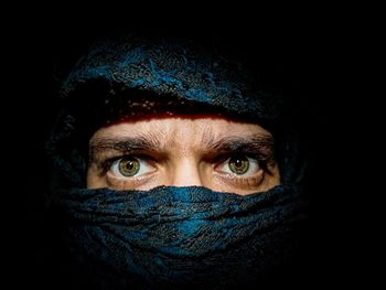 Close-up of man wearing mask against black background