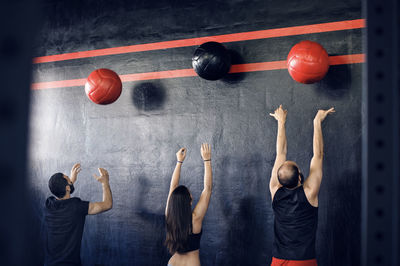 Rear view of athletes exercising with medicine balls in gym