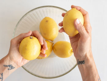 Cropped hands holding lemons over bowl