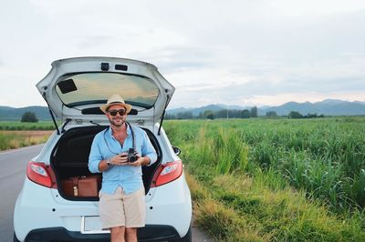 Man with camera on field against sky