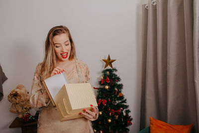 Woman holding christmas tree at home