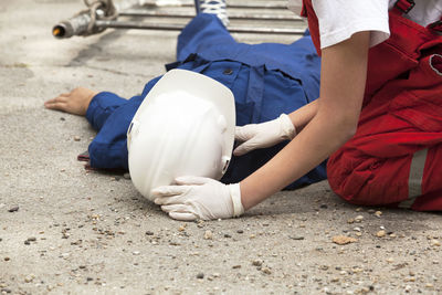 Paramedic performing cpr on person lying on street