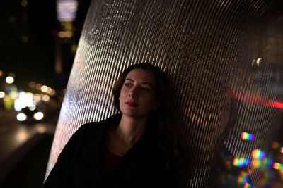 Mid adult woman leaning on pillar in city