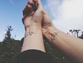 Cropped hand of couple with tattoo