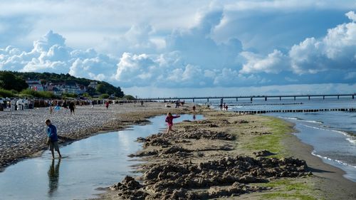 People at beach against cloudy sky