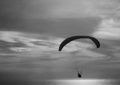 Silhouette person by sea against sky