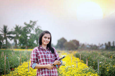 Young woman smiling while standing on field against sky