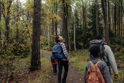 Parents exploring forest with children while walking on trail during vacation